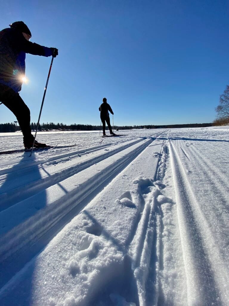 Hiihtäjät kirkkojärven jäällä, sininen taivas