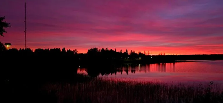 Auringonlaskun jälkeen Kirkkojärvellä, leirintä-alueen valot loistaa järven takaa